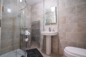 A bathroom with a glass shower enclosure, a white sink, and a toilet.