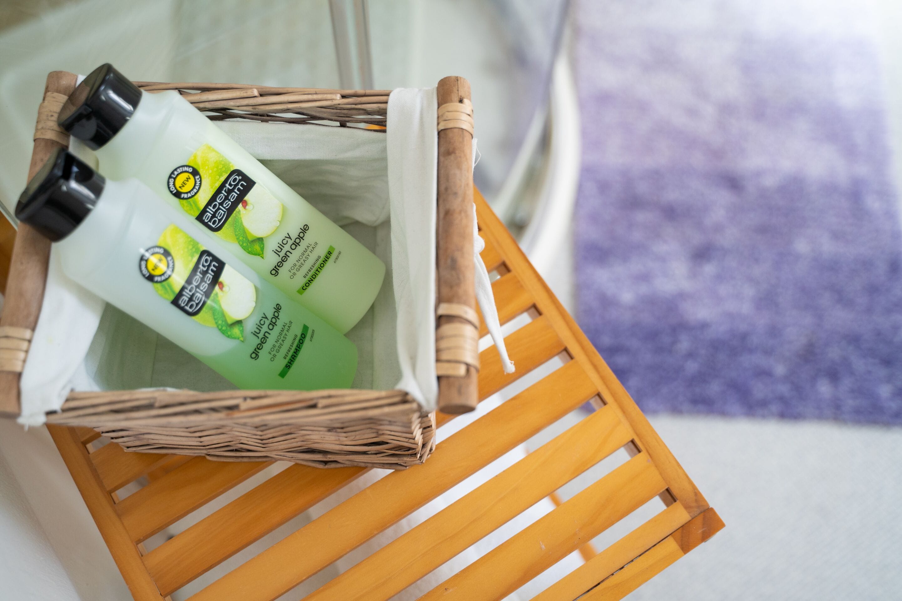 Un panier en osier contenant deux flacons de lotion pour le corps Alberto Balsam, parfum pomme verte.