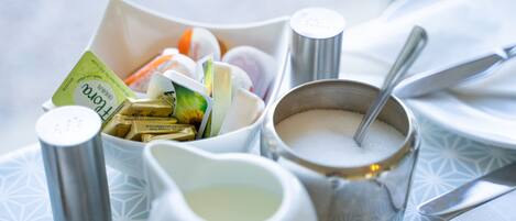 A table setting with a salt shaker, sugar bowl, and a white pitcher.