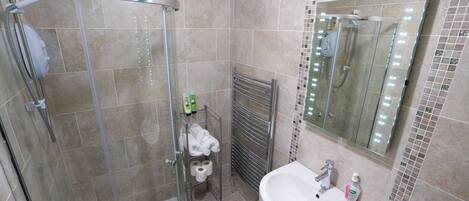 A modern bathroom with a glass-enclosed shower, a white sink, and a mirror with lights.