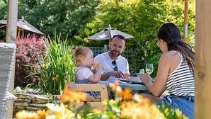 A family dining outdoors at a table with a garden view. - The Highdown Inn (Totland Bay)