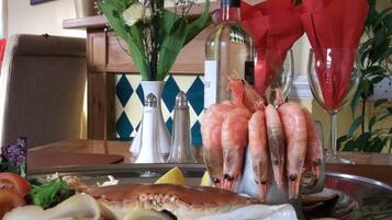 A seafood platter with shrimp, oysters, and other seafood on a tray, accompanied by a bottle of white wine and a glass of red wine.