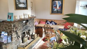 A cozy room with a stone fireplace, a wooden bench, and a table with chairs. - The Highdown Inn (Totland Bay)