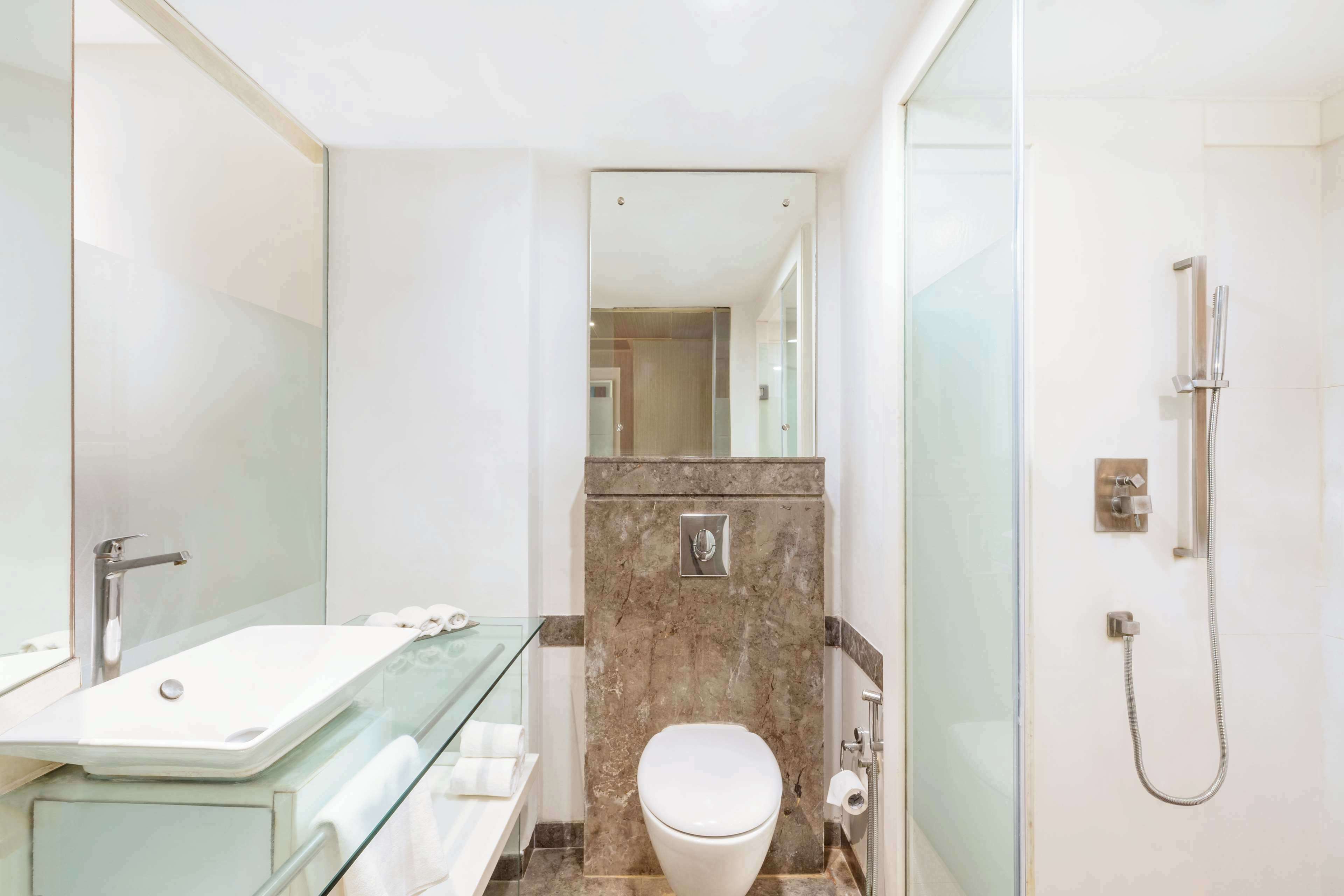 A modern bathroom with a glass shower enclosure, a white sink, and a marble-topped vanity.