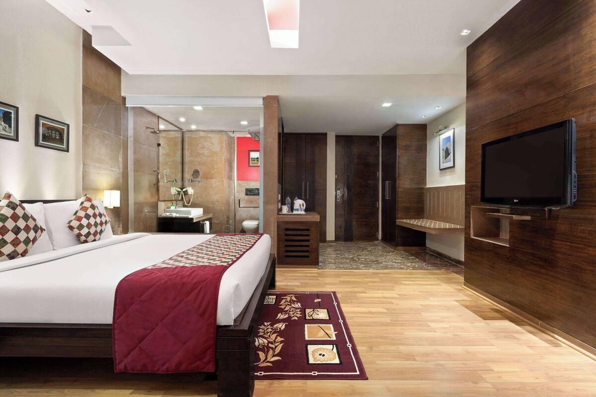 Une chambre d’hôtel moderne avec un grand lit, une télévision, une salle de bain avec douche et un mur en bois.