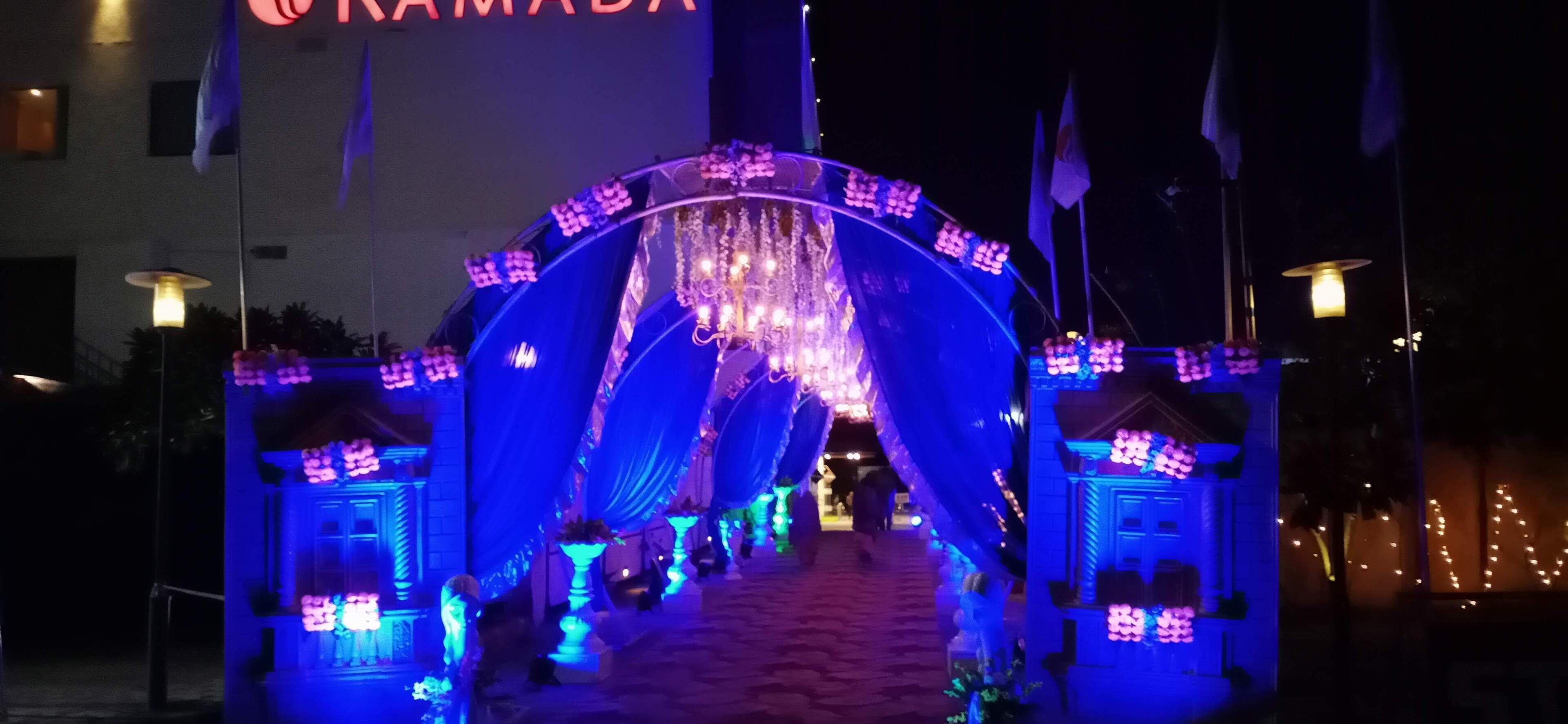 Un arco con iluminación azul y adornos colgantes, que conduce a la entrada de un edificio.