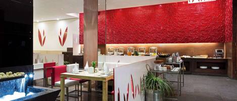 Un moderno vestíbulo de hotel con una pared texturizada de color rojo, un mostrador de recepción y un comedor con una cascada.