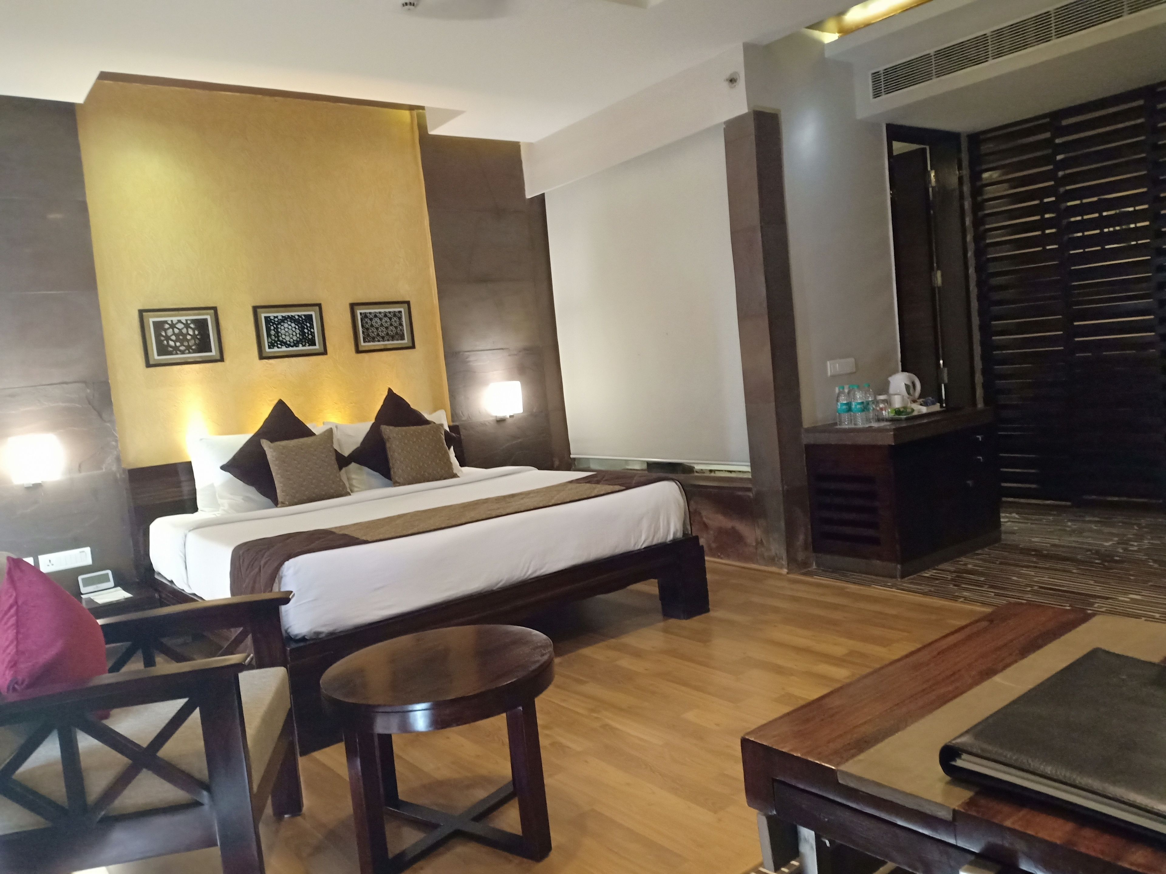 A hotel room with a bed, bedside table, chair, and a small round table.
