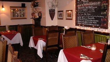 A restaurant interior with tables set for dining, a chalkboard menu, and framed artwork on the walls.
