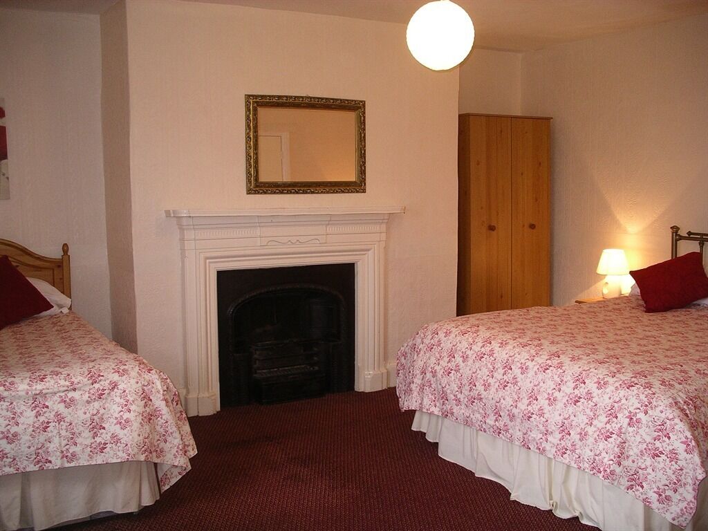 Una habitación de hotel con dos camas, una chimenea, un armario de madera y un espejo en la pared.