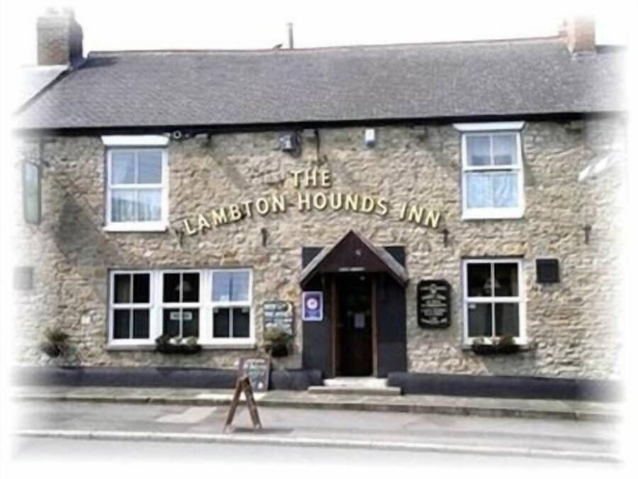 The Lambton Hounds Inn, a stone building with a traditional design, featuring a prominent entrance and signage.