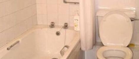 A bathroom with a bathtub, toilet, and a window with flowers.