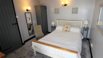 A bedroom with a bed, a chair, a wardrobe, and two bedside tables with lamps.