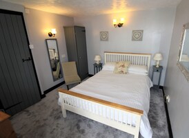 A bedroom with a bed, a chair, a wardrobe, and two bedside tables with lamps.