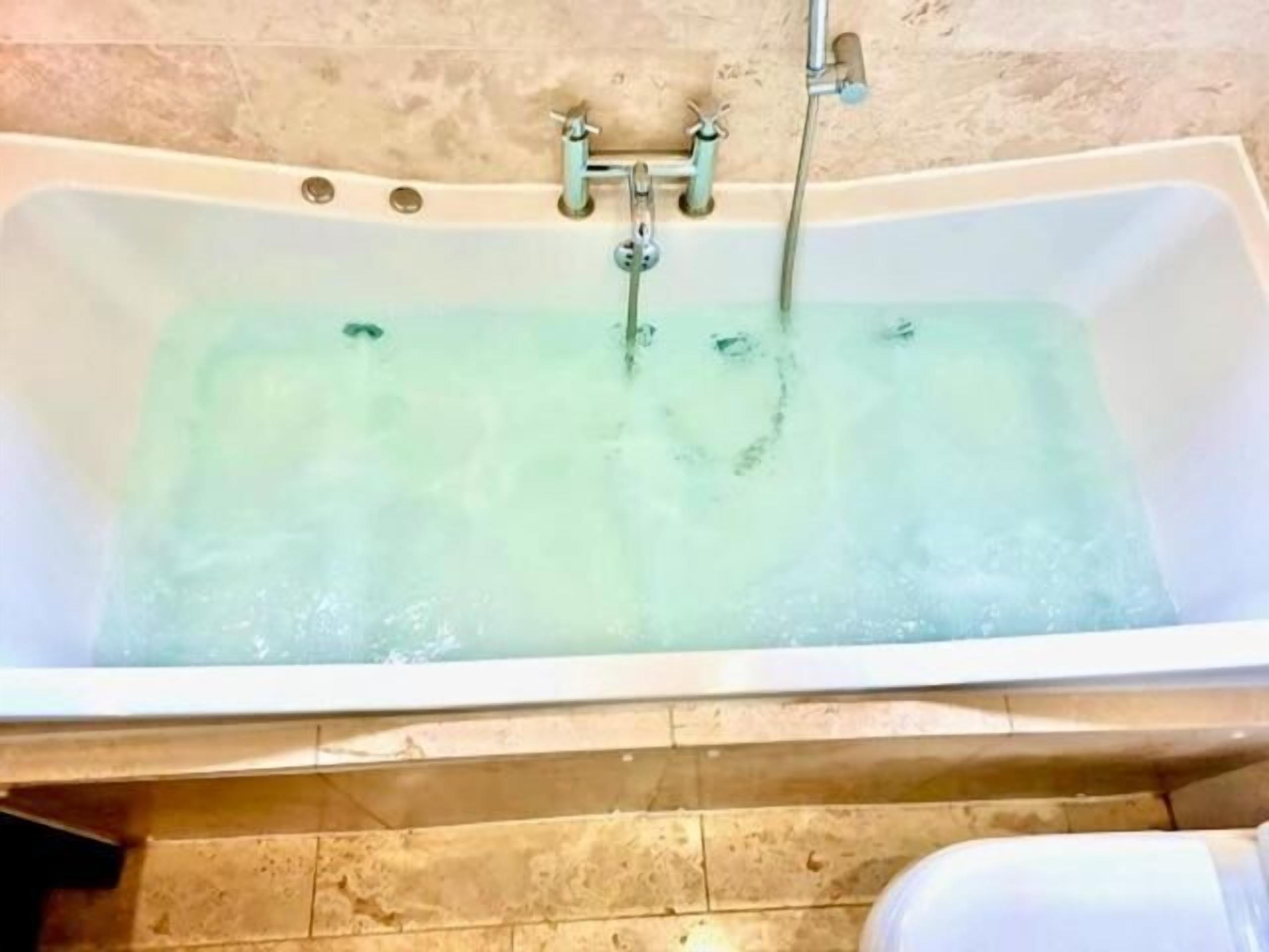 A bathtub with running water, a showerhead, and a faucet.