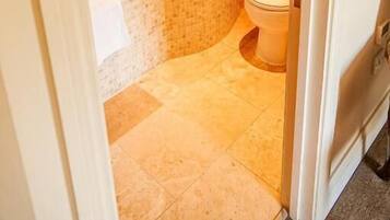 A bathroom with a glass-enclosed shower, a freestanding bathtub, and a toilet.