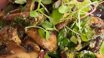 A dish with asparagus, mushrooms, and greens on a red plate.