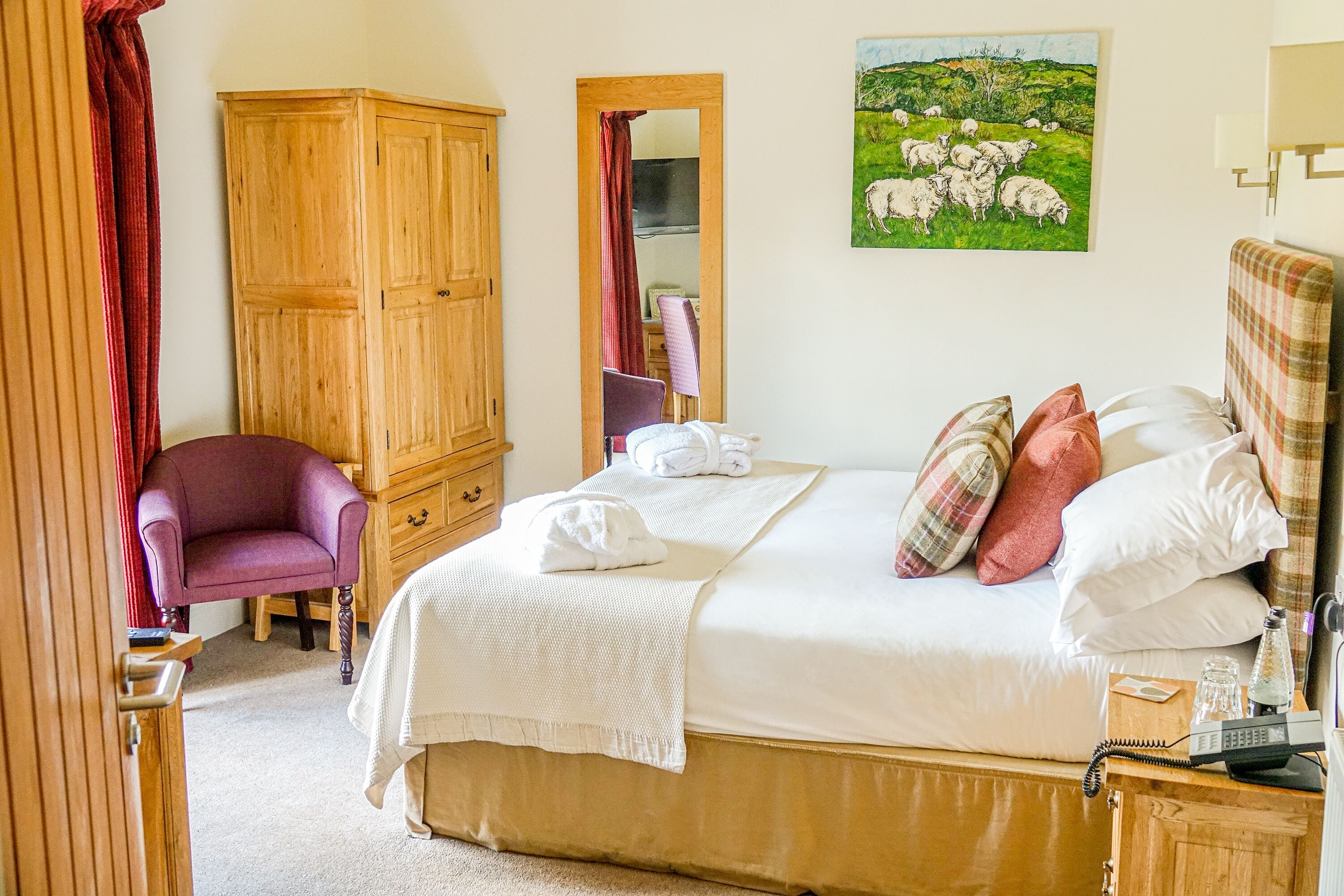 A bedroom with a bed, a wardrobe, a chair, and a painting on the wall.