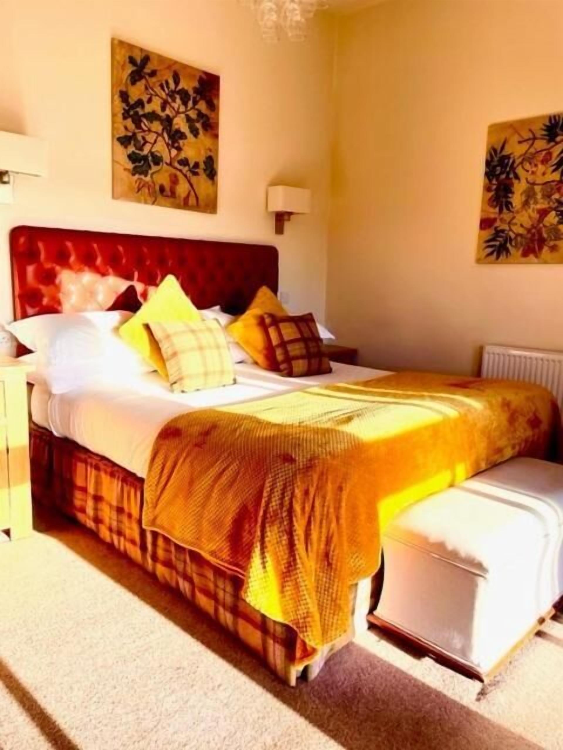 Una habitación de hotel con una cama grande, una mesita de noche y dos lámparas fijadas a la pared.