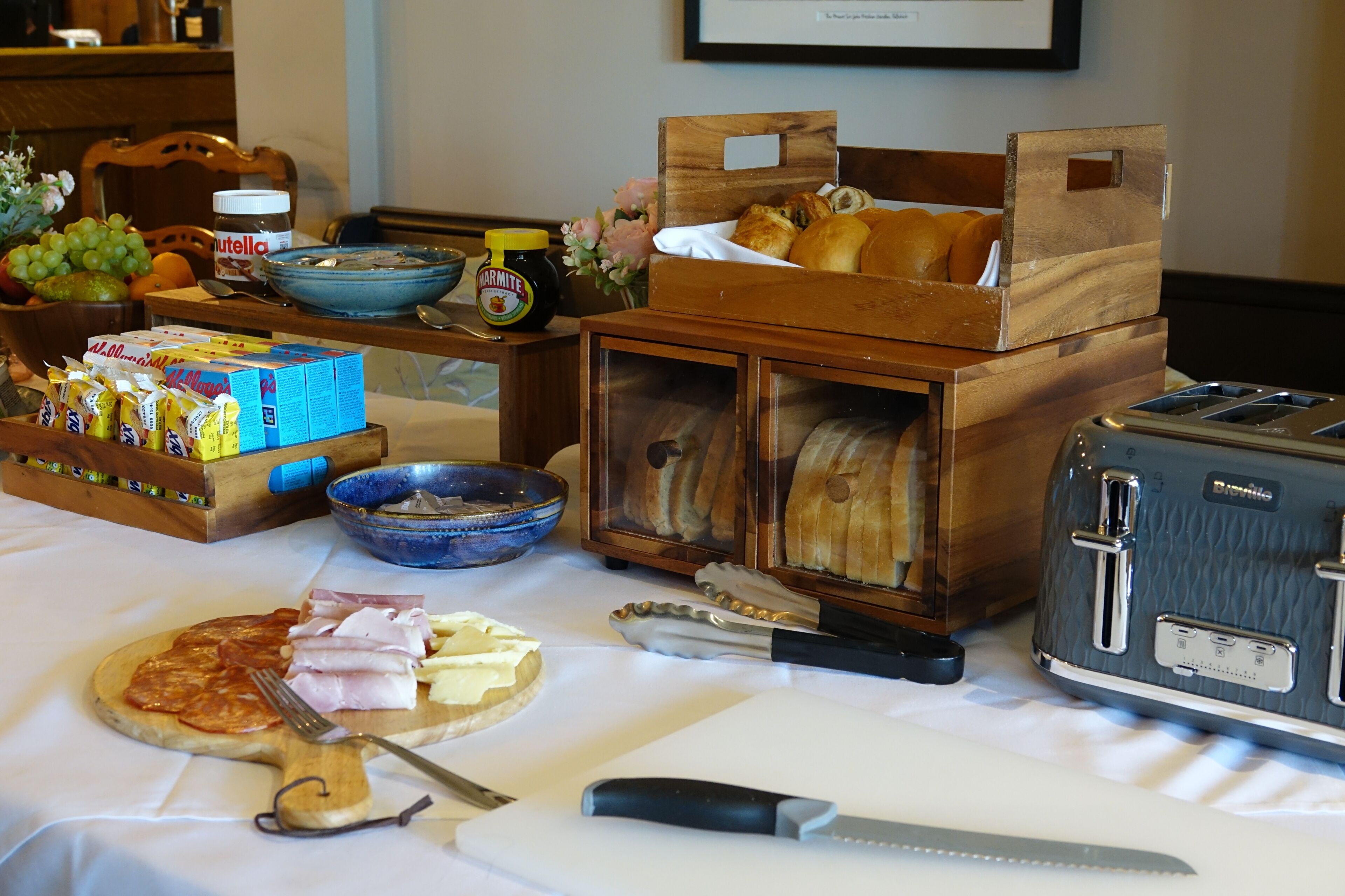 Un buffet de petit-déjeuner avec divers aliments, un grille-pain et un couteau sur une table.