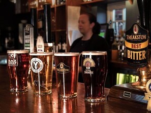 Un bar amb diversos vasos i torneires de cervesa, incloent marques com Black Sheep, Theakston i John Smith's Extra Smooth.