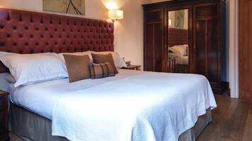 A large bed with a tufted headboard, a bedside table, and a nightstand.