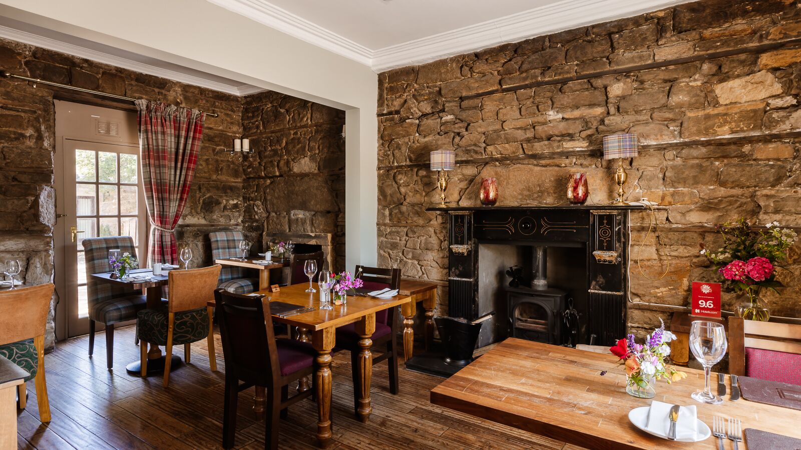 Un comedor rústico con pared de piedra, muebles de madera y chimenea.