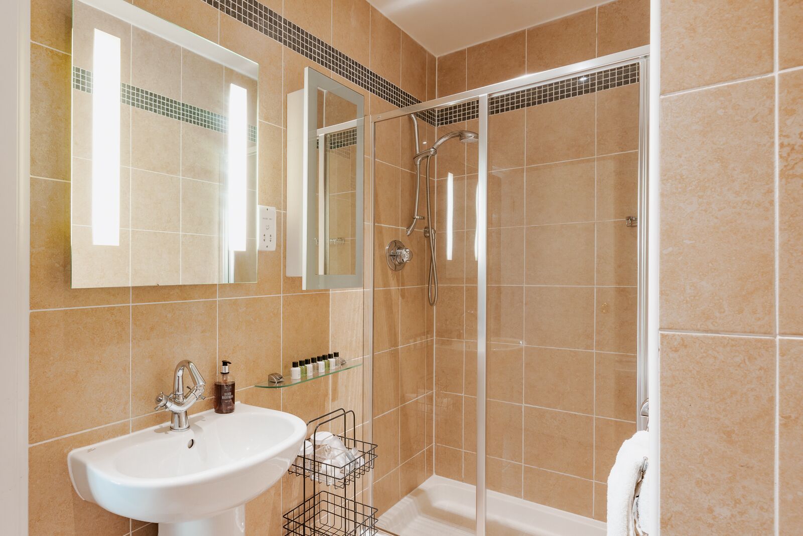 A bathroom with a white sink, a mirror, a glass shower enclosure, and a towel rack.