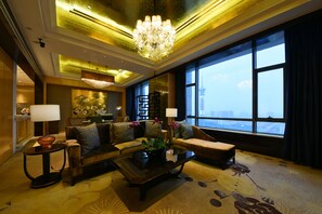 A spacious living room with a large window, a chandelier, and a sofa set.