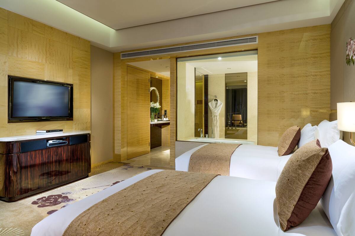 Een hotelkamer met twee bedden, een televisie, een bureau en een spiegel.