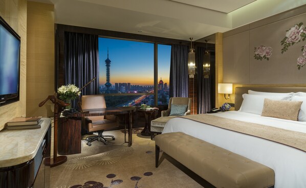 Hotelkamer met een groot bed, een bureau met stoel, uitzicht op een stadsbeeld en een stadsgebouw.