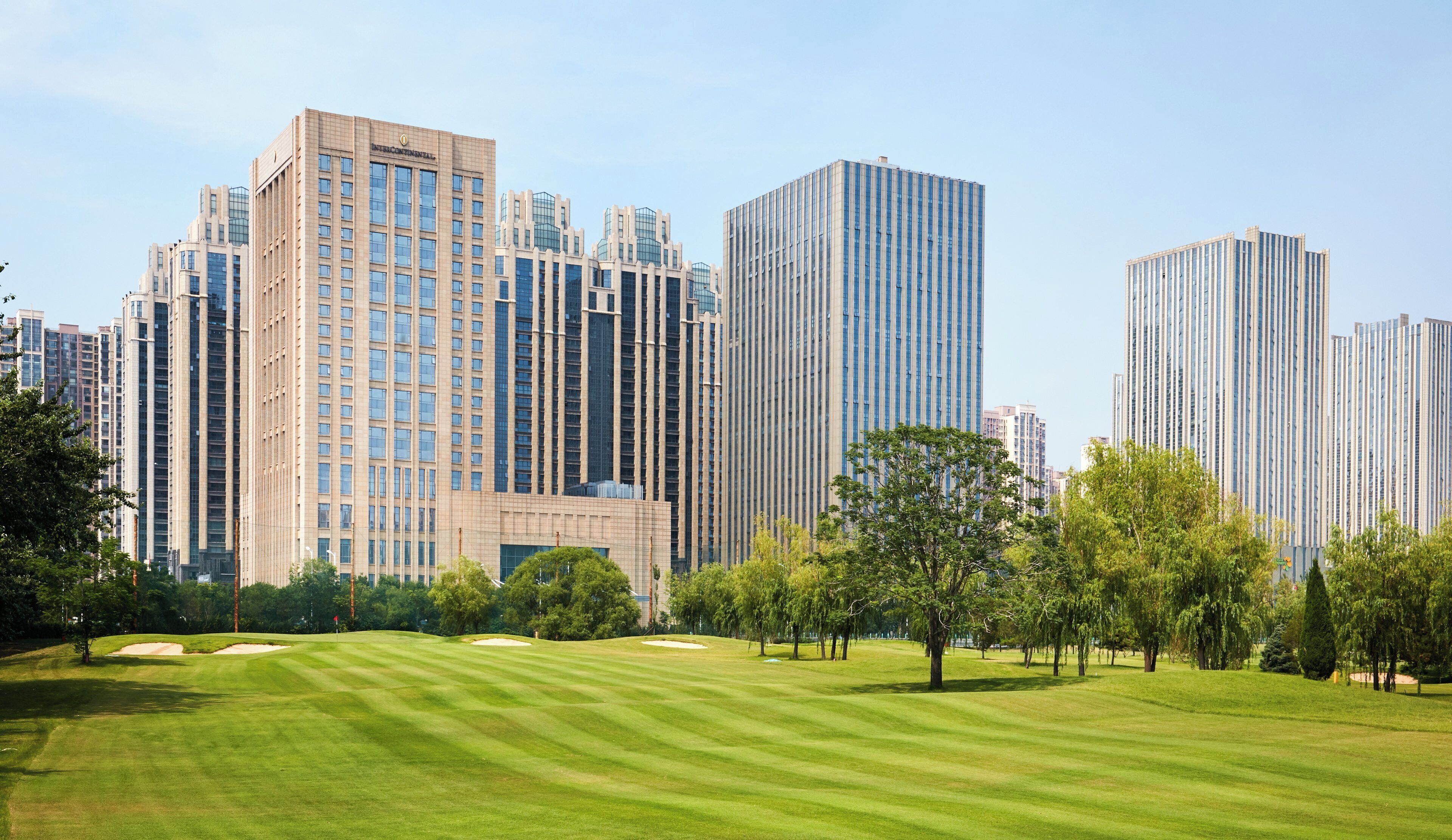 A golf course with modern high-rise buildings in the background.