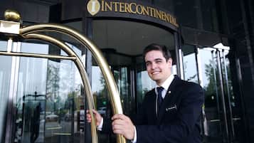 A man in a suit at the entrance of a building with a sign that reads "INTERCONTINENTAL".