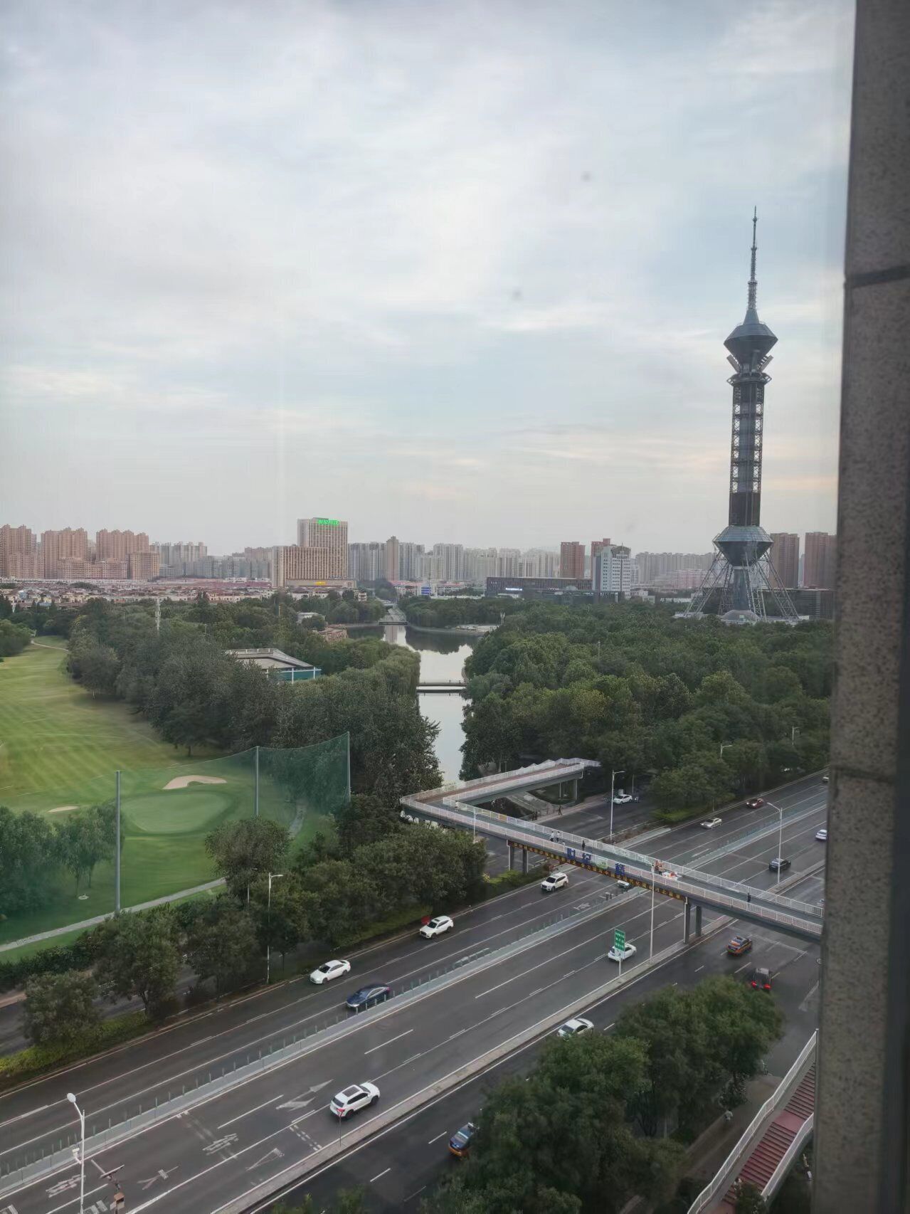 A cityscape with a prominent tower, a river, and a highway with vehicles.