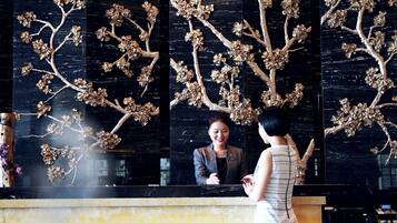Un espace d’accueil avec un mur en marbre noir et une sculpture d’arbre décorative.