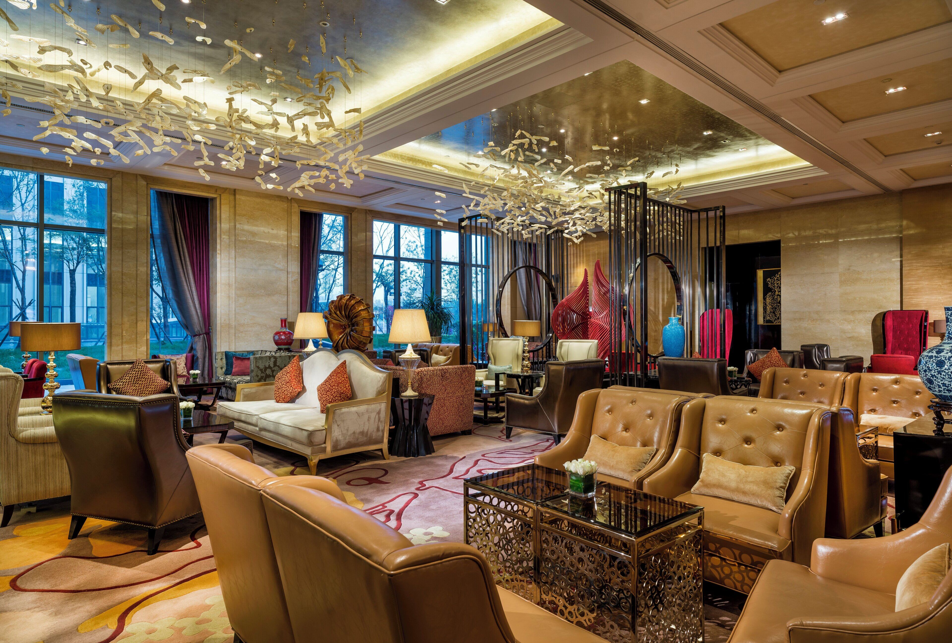 A spacious lobby with leather seating, a central coffee table, and a decorative ceiling installation.