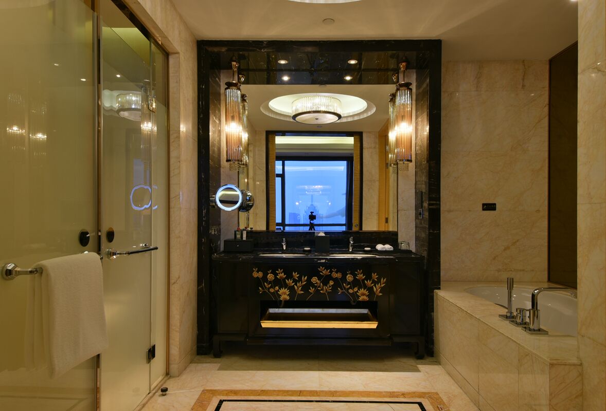 A modern bathroom with a large mirror, two sinks, and a chandelier.