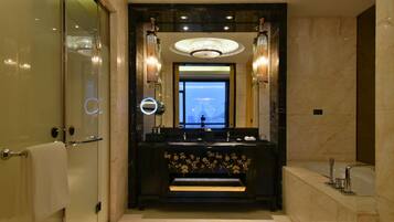 A modern bathroom with a large mirror, two sinks, and a chandelier.