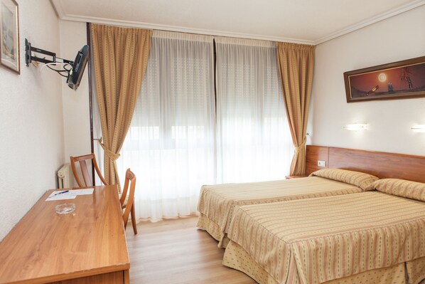 A hotel room with two beds, a wooden desk, and a chair. - Hotel Las Anclas (El Astillero)