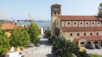A building with a tower, a parking area, and a road leading to a body of water.