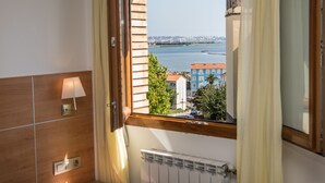 Habitación con vista a un cuerpo de agua y edificios al otro lado.
