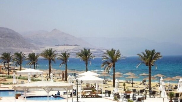 Un complejo turístico con piscina, sombrillas de playa y palmeras.