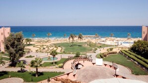 Un resort con piscina, palmeras y vista al mar.