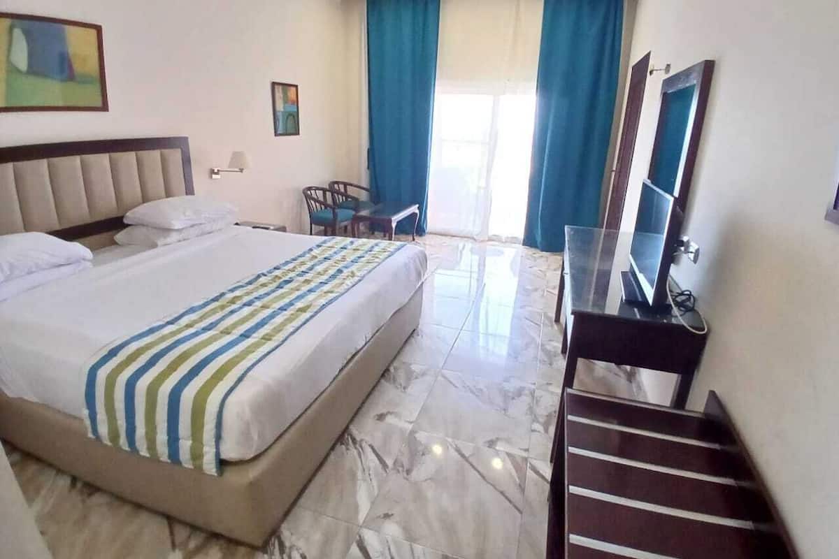 Una habitación de hotel con una cama, un escritorio, una silla, un televisor y una escalera.