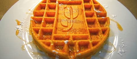 A waffle with syrup on a white plate.