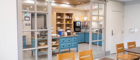 Una cocina moderna con armarios azules, una mesa de comedor de madera y un ventanal corredero que da a una zona de comedor.