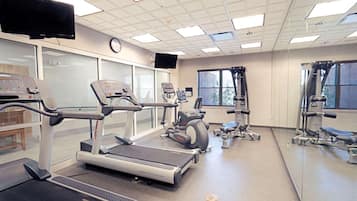 Un gimnasio con cintas de correr, elípticas y equipo de pesas.