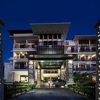 A multi-story hotel with a modern architectural design, featuring balconies and a covered entrance.