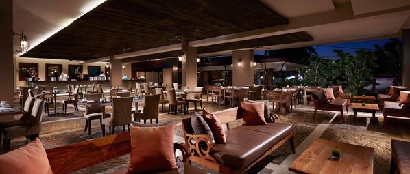 A spacious outdoor dining area with multiple tables and chairs, a bar area, and a lounge with sofas and a coffee table. - Sun Island Hotel & Spa Kuta (Kuta)