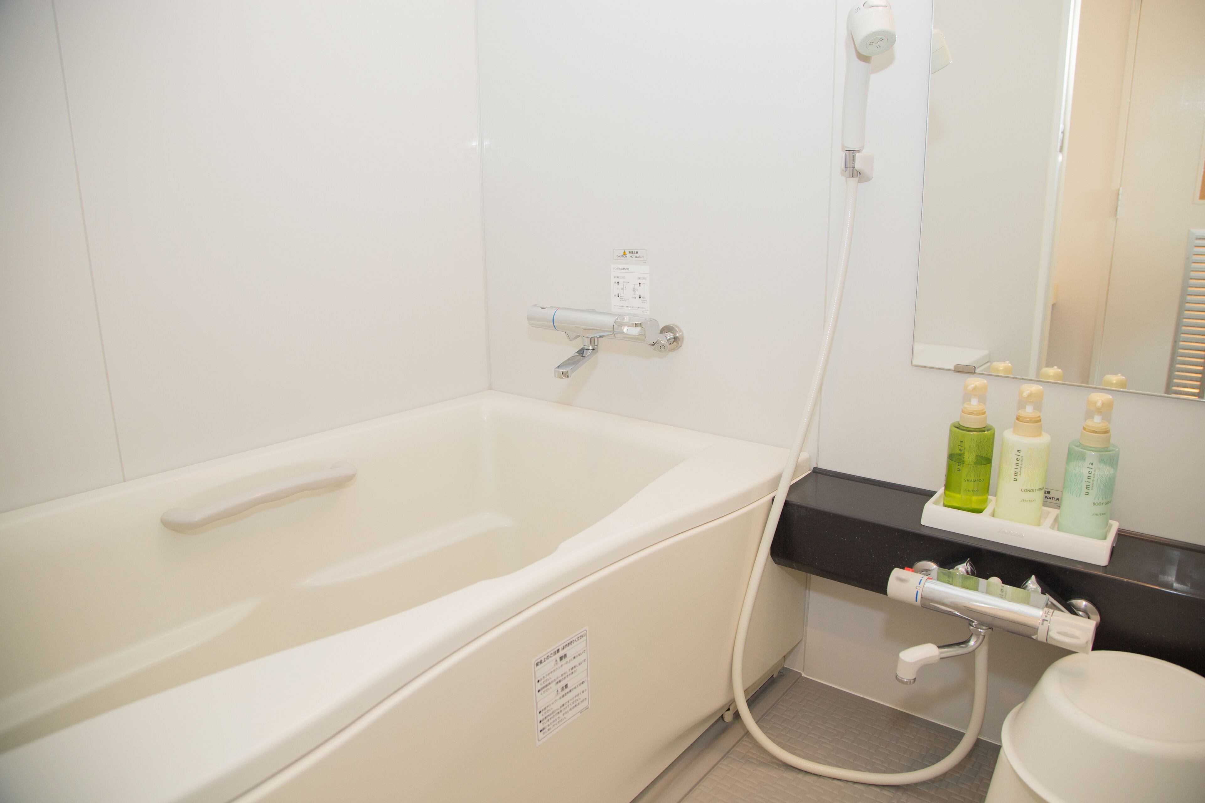 A bathroom with a bathtub, a shower, and a sink. There are toiletries on the counter.